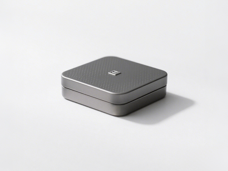 Square light gray box, dotted surface, with a small square logo in the center, low-key with details.