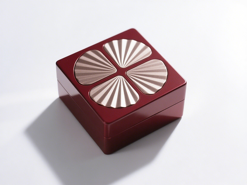 Square red box, lid’s four golden radial - textured parts distribute like a flower, striking color contrast, unique shape.
